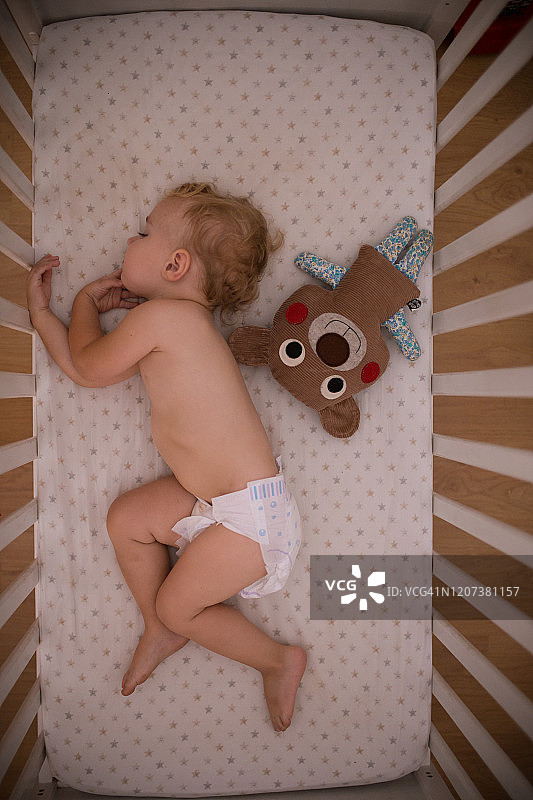 在泰迪熊旁边小睡的男婴图片素材