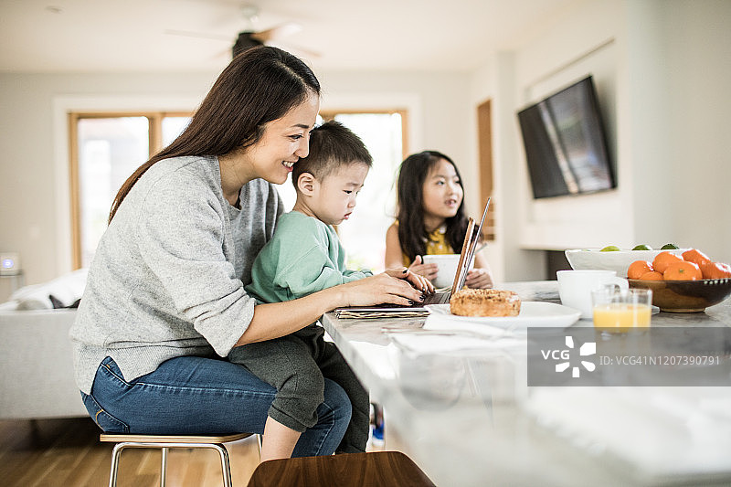 母亲在厨房的餐桌上照顾年幼的孩子们图片素材