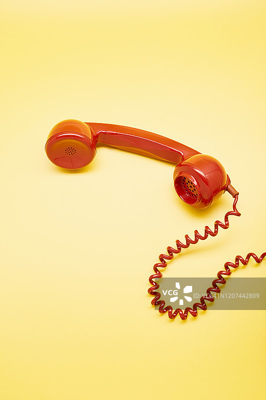 黄色背景上的红色老式电话听筒高视角图片素材