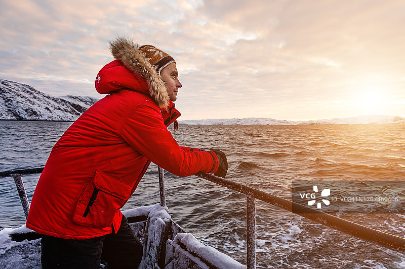 冬天在北极的船上穿着红色夹克的男人图片素材