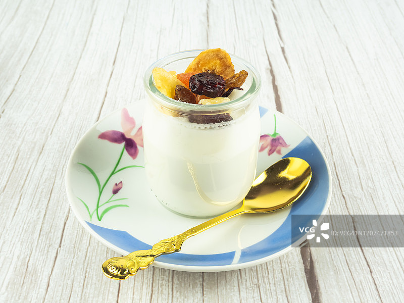 一杯含水果干的酸奶和金色勺子图片素材