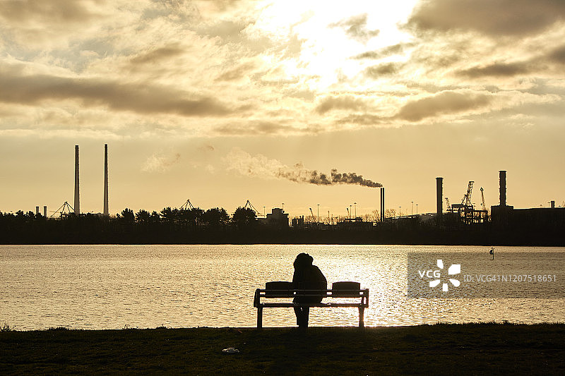一位女士坐在爱尔兰都柏林克朗塔夫海滩的长椅上图片素材