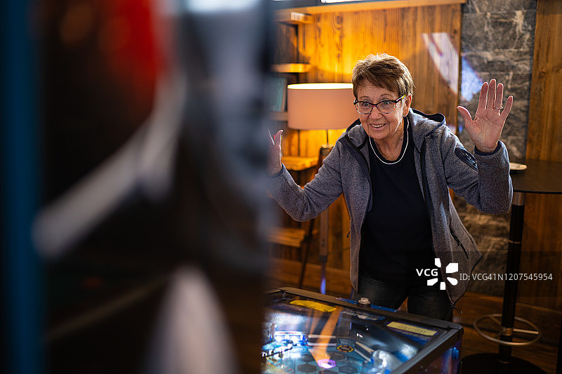 在弹球机上玩游戏的年长女人图片素材