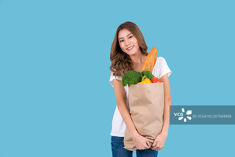 手提装满蔬菜的购物袋的微笑亚洲女性图片素材