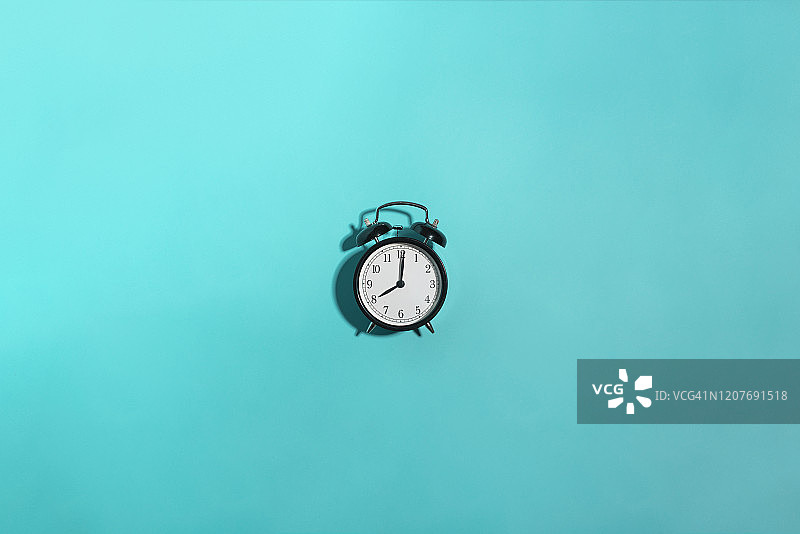蓝色背景上的黑色闹钟图片素材