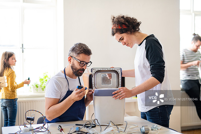 一群在社区中心修理家用设备的人。图片素材