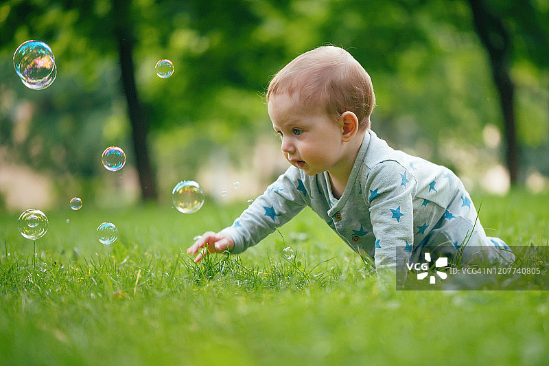 在夏日公园里玩泡泡的男婴图片素材