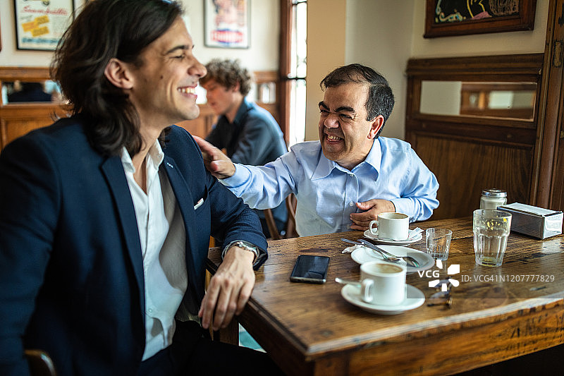 患有侏儒症的男子清晨在当地咖啡馆与朋友玩耍图片素材