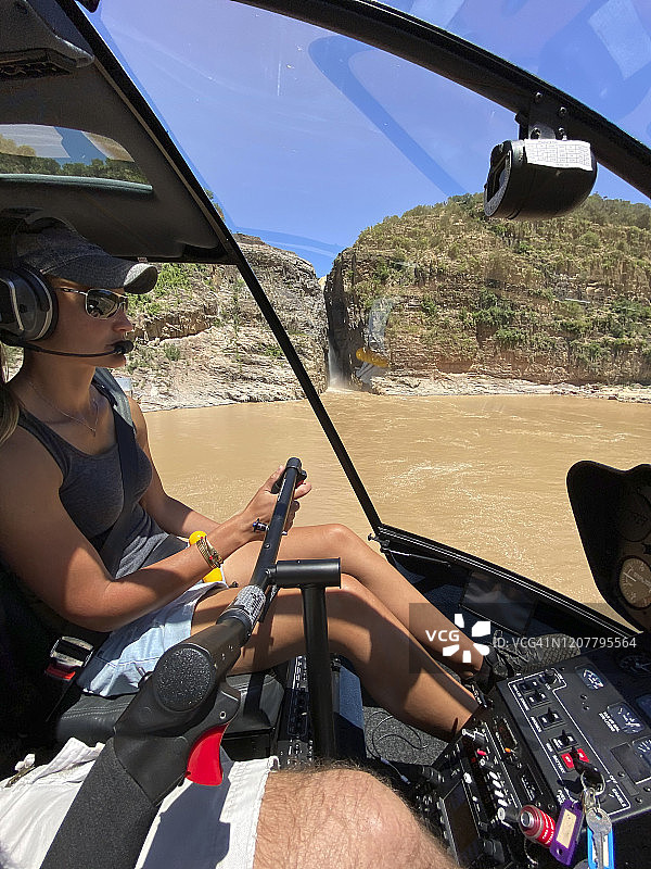 女直升机飞行员飞越豪威克瀑布上方的湖面图片素材