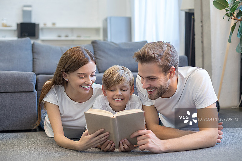 幸福的年轻家庭在房间里一起看书图片素材