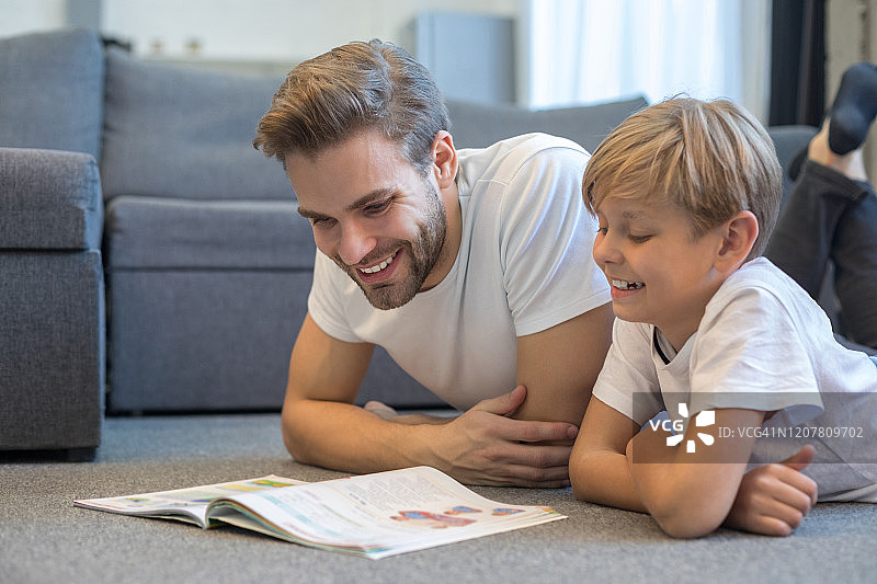 快乐的年轻父亲在室内帮助孩子完成任务图片素材