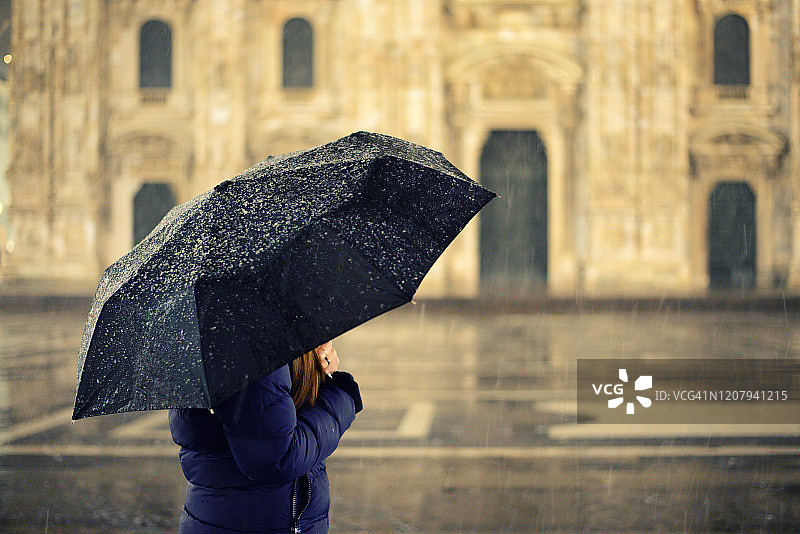 冬夜，灯光下，女孩打着伞在雪中慢跑图片素材