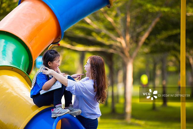 母亲和孩子们在游乐园享受阅读时光图片素材