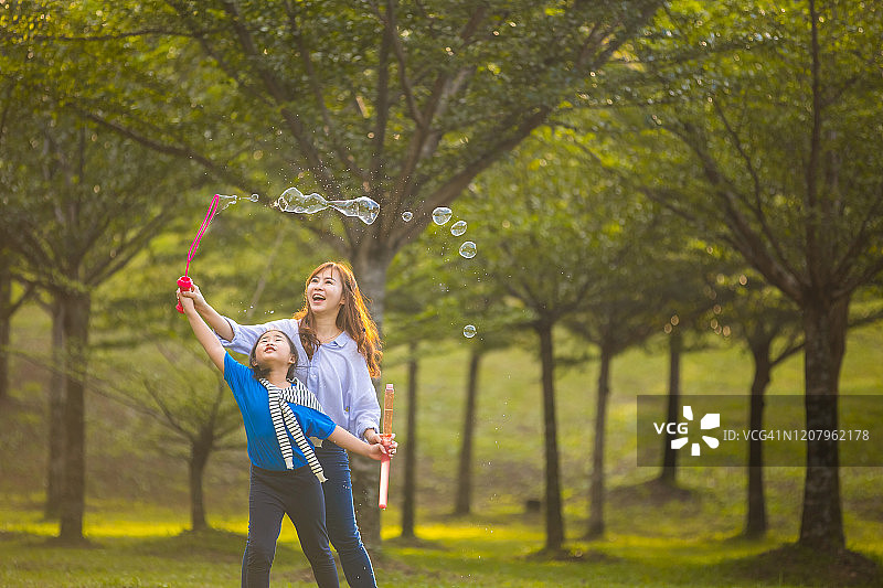 母亲和孩子们在公园里玩肥皂泡图片素材