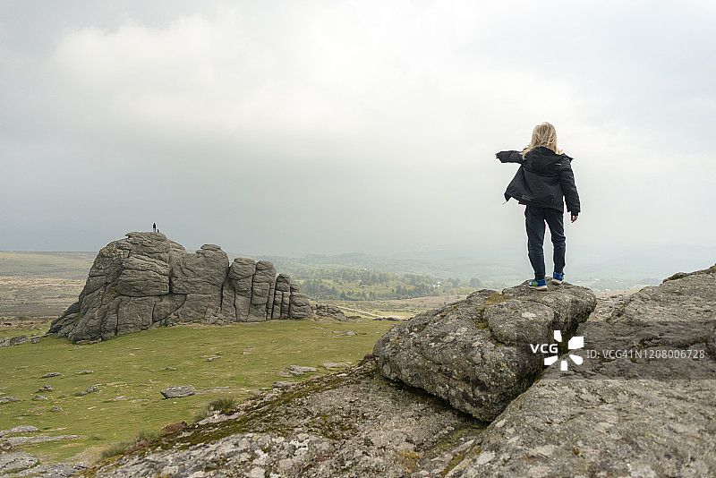 在英国达特穆尔海托岩石上指点的男孩图片素材