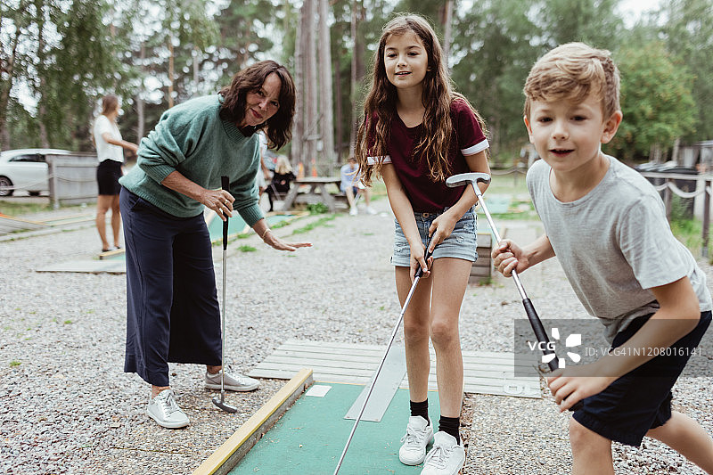 兄妹在后院与家人玩迷你高尔夫图片素材