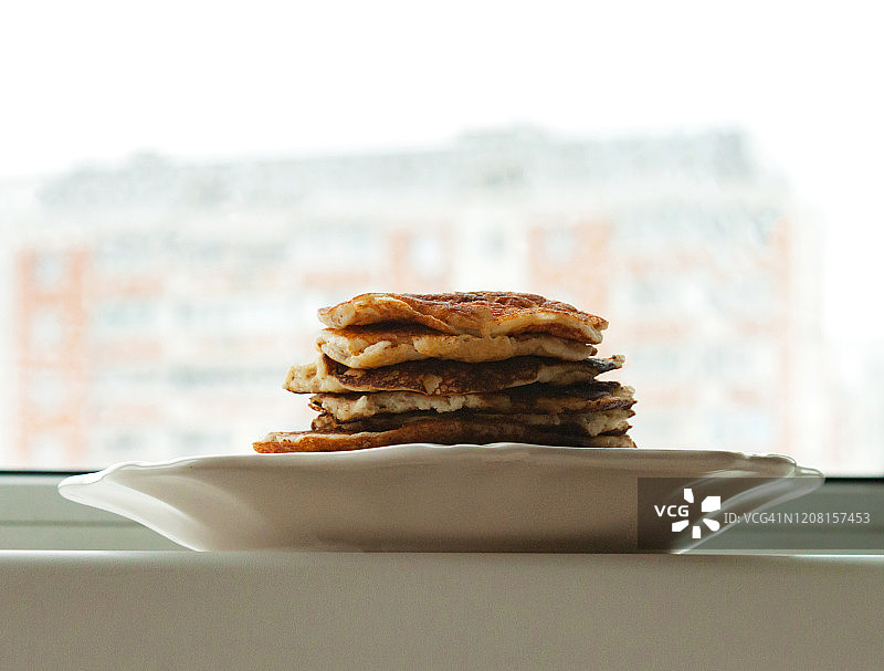 用杏仁椰子粉制作的低碳水化合物酮饮食煎饼，白色盘子上，背景是密封的城市图片素材