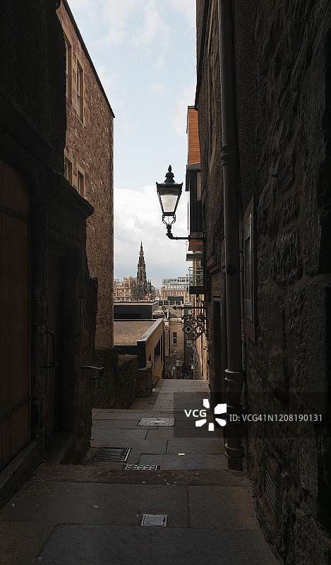 英国苏格兰爱丁堡的巷道，背景是司各特纪念碑和前景是路灯图片素材