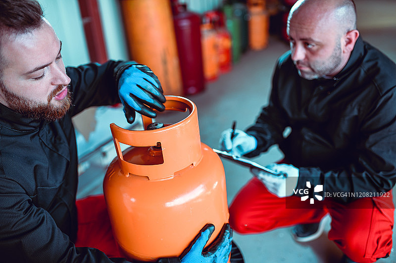 两位男工人记录气瓶的生产日期图片素材