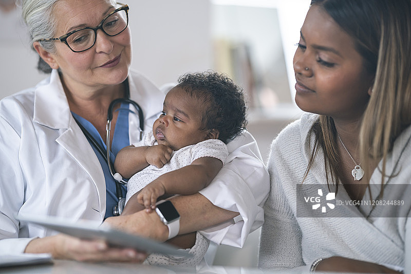 儿科医生在平板电脑上与年轻母亲一起查看测试结果图片素材