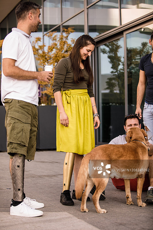 使用腿部假肢的人与狗站立的特写图片素材
