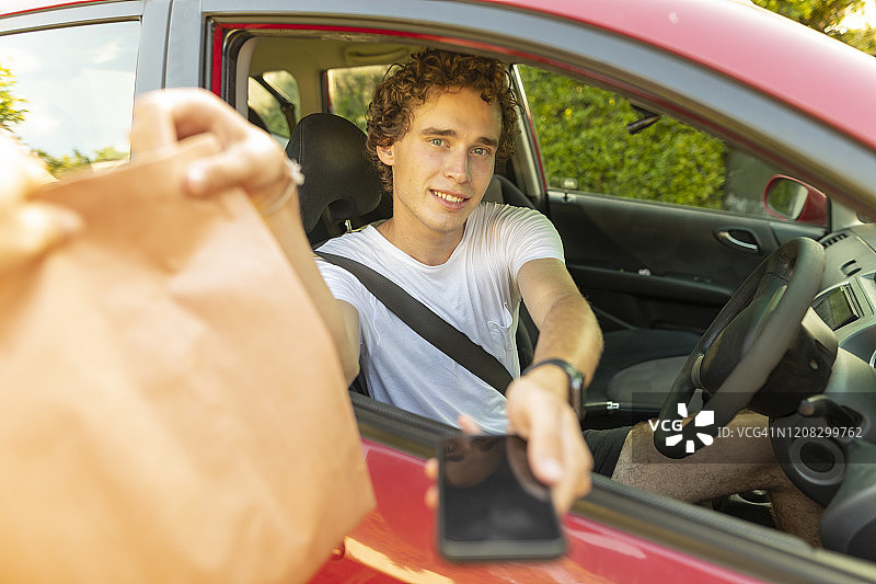 年轻男人使用非接触式支付购买外卖食品图片素材