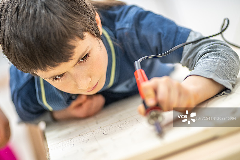 专注的年轻男孩用烙笔在木板上写数字图片素材