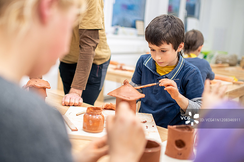 在课堂上用粘土制作鸟屋的男学生图片素材