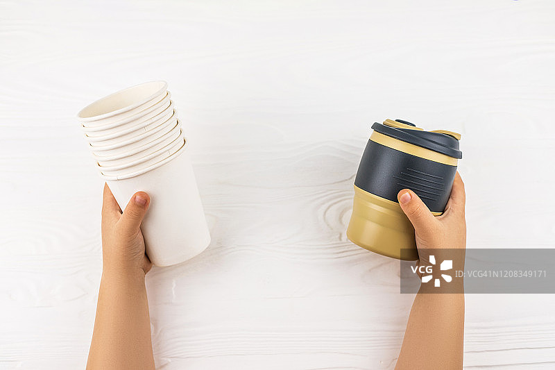 儿童的手拿着可重复使用的杯子和一次性杯子图片素材