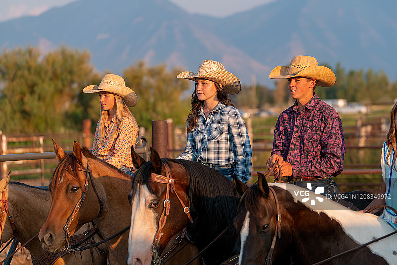 一群年轻的牛仔和女牛仔在日落时骑马图片素材