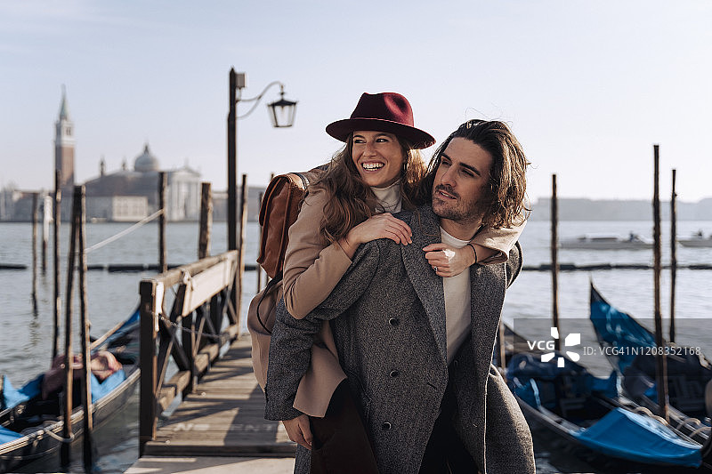 年轻男人在意大利威尼斯海滨给女友背背图片素材
