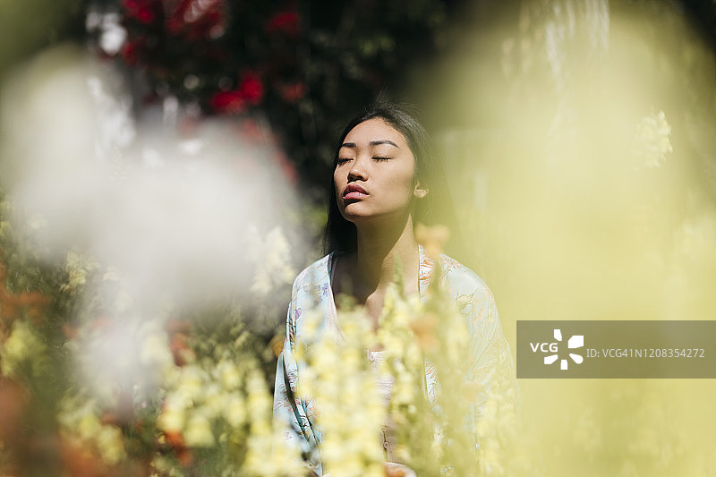 美丽的年轻女子在春天被花园里的鲜花簇拥图片素材