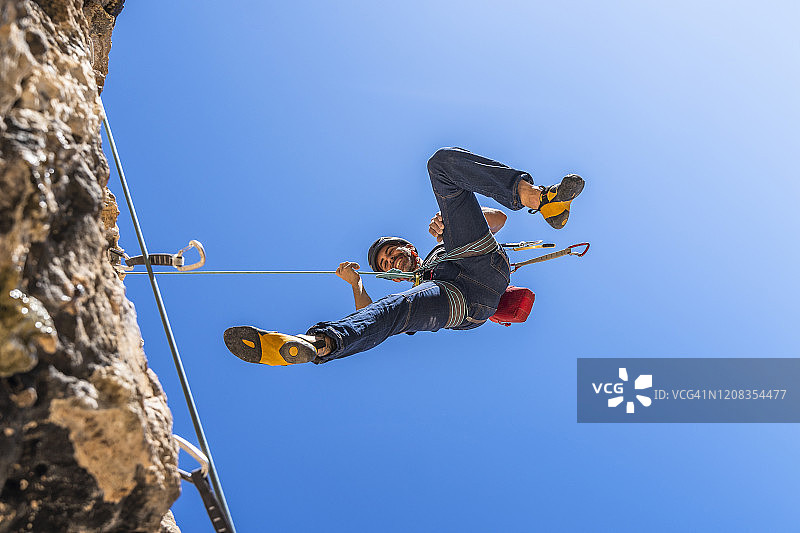 微笑的登山者从岩壁上绳降图片素材