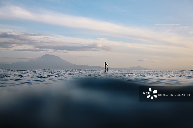印度尼西亚巴厘岛阿贡火山背景下的桨板冲浪图片素材