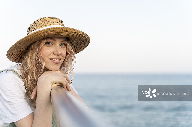 年轻女子在海边度过一天，倚靠在栏杆上，肖像照图片素材