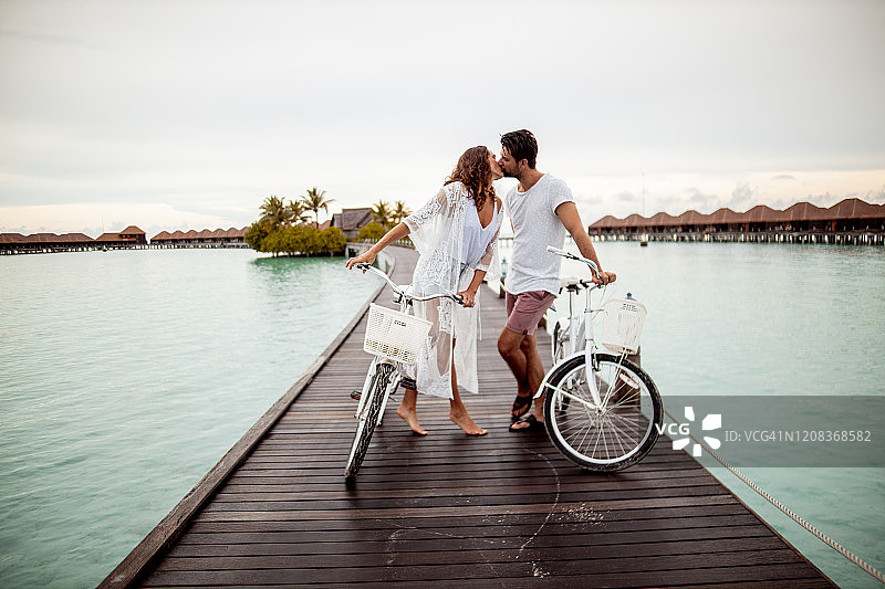 情侣在马尔代夫Gaafu Dhaalu环礁Maguhdhuvaa岛的码头上骑自行车接吻图片素材