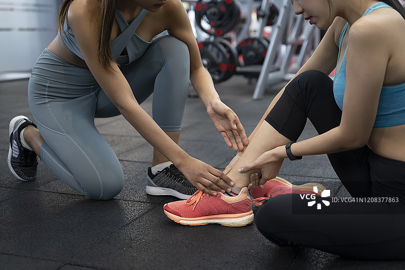 运动女人和私人教练在健身房，其中一人脚踝受伤图片素材