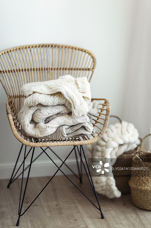 柳条扶手椅上堆放着舒适的羊毛白色针织毛衣图片素材