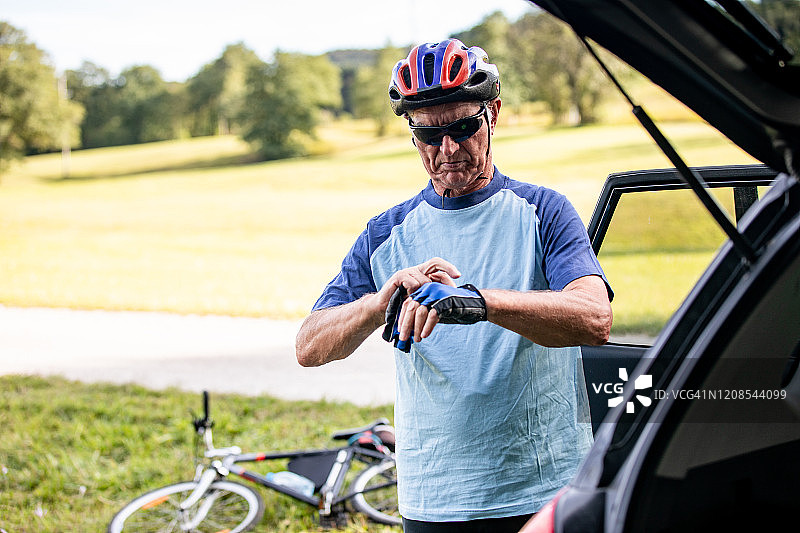 在乡村公路旁，准备骑行的活力老年男人图片素材