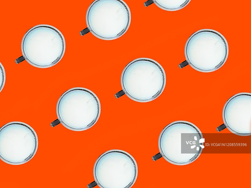 橙色背景下的成排牛奶杯图片素材