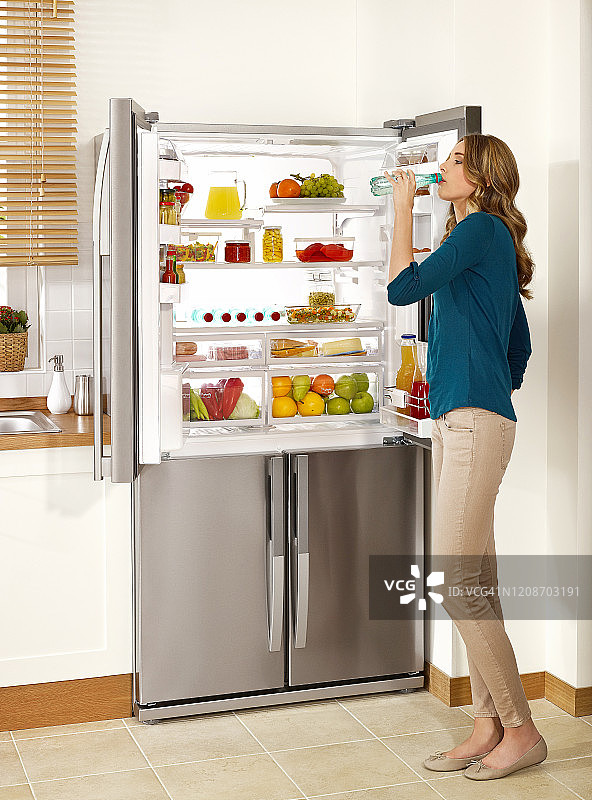 从冰箱里取水喝的女人图片素材