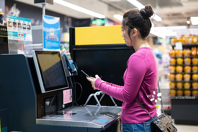 亚洲女性在超市的自动支付机上进行非接触式支付图片素材
