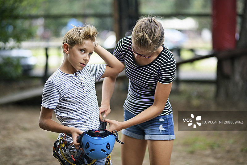 少女帮助她的兄弟穿戴安全带图片素材