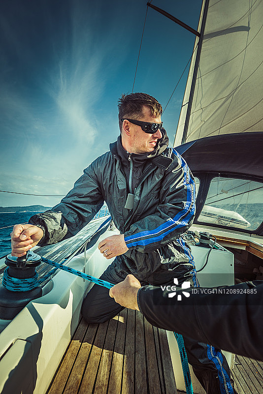 在帆船上使用绞盘的男人图片素材