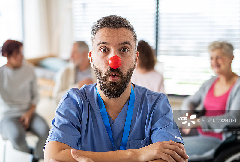 医院里戴着红色小丑鼻子的医生肖像，背景是病人图片素材