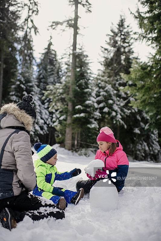 兄妹在冬日堆雪人图片素材