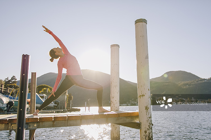 女人在湖边码头上做瑜伽图片素材