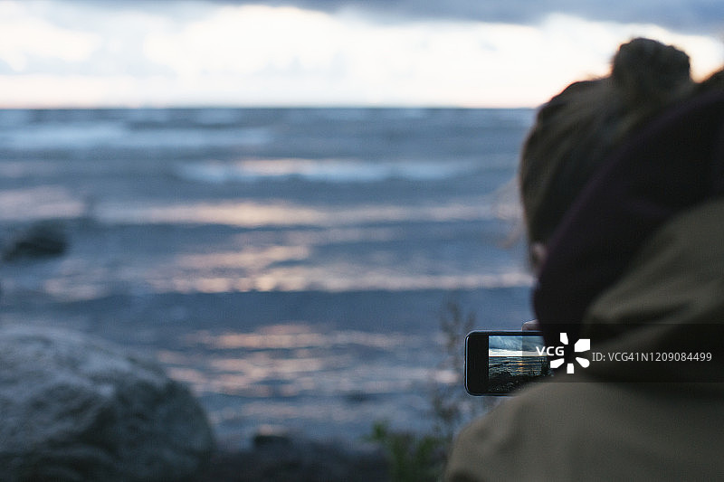 女人用手机拍摄大海图片素材