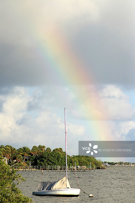 沿海内陆水域的彩虹，可见船坞、船只和热带树木图片素材