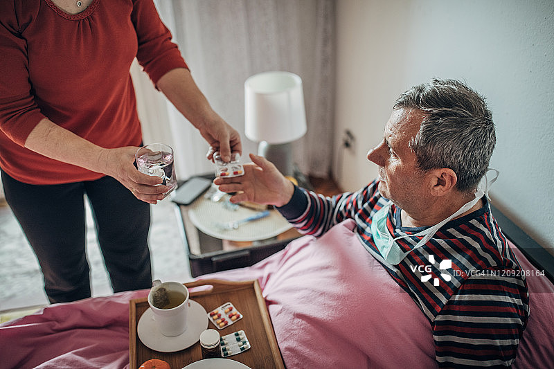 生病的男人正在喝水吃药图片素材